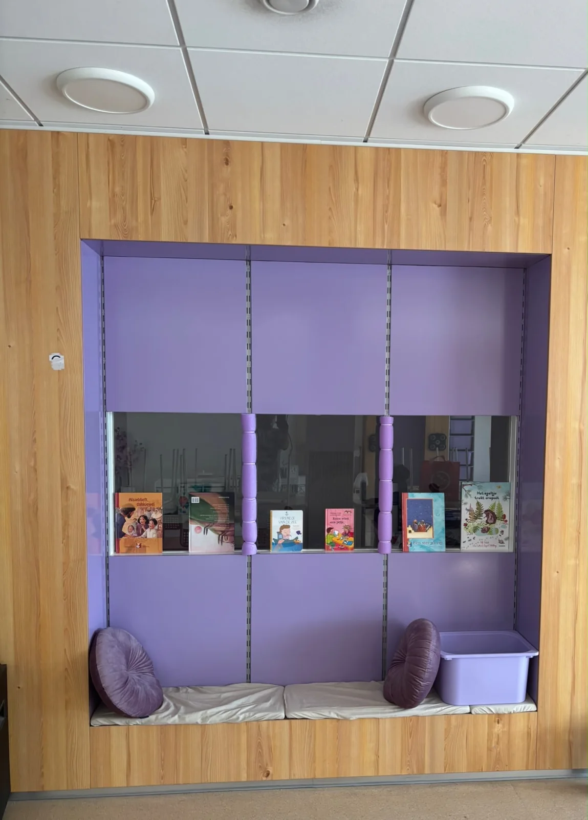 Paarse leeshoek met kinderboeken en zitkussens bij Heavenly Angels BSO